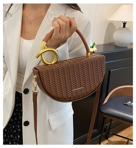 Détail du sac bandoulière marron tressé avec poignée torsadée en métal doré