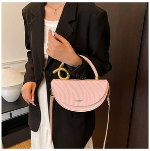 Detail of light pink curved bag with gold twisted handle and leather texture shown on model