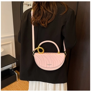 Detail of pink semi-circular handbag with wavy texture and gold ring hardware