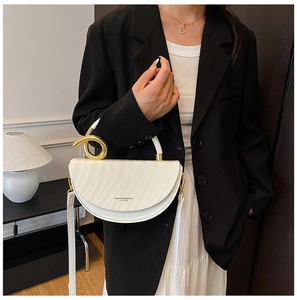 Detail of white saddle bag with wavy texture and unique twisted gold metal handle