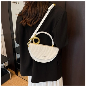 Detail of white saddle bag with wavy texture and gold ring hardware on black coat