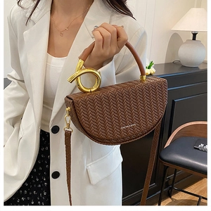 Détail de la texture tressée et poignée en métal doré du sac besace marron