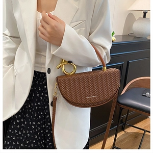 Détail d'un sac besace marron tressé avec poignée ronde dorée et bandoulière