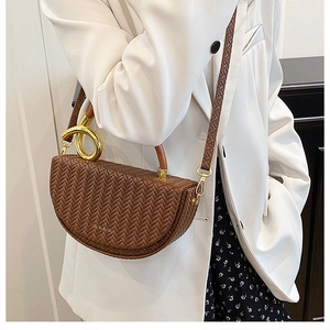 Sac bandoulière tressé marron avec poignée dorée porté sur blazer et robe à fleurs