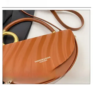 Detail of a brown semi-circle box bag with wavy texture and golden ring handle