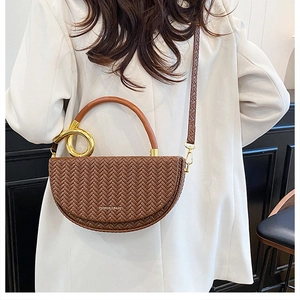 Détail de la texture tressée marron et anneau doré sur un sac demi-lune chic