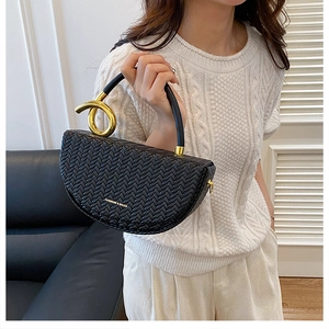 Détail du sac en cuir tressé noir avec une boucle métallique dorée volumineuse