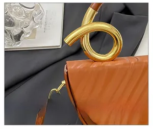 Detailed macro view of brown embossed leather and golden spiral handle on a retro handbag