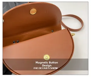 Detail of the golden magnetic button closure on a vintage brown saddle bag strap