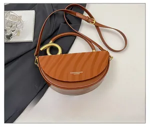 Detail of brown half-moon bag with wave texture flap and gold circular metal handle