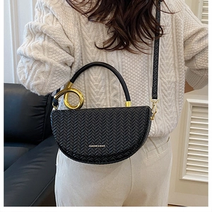 Détail du sac demi-lune tissé noir avec poignée à anneau doré et bandoulière fine