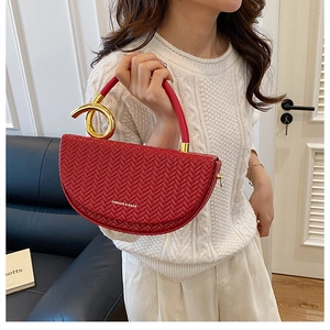 Détail du sac selle tissé rouge avec nœud en spirale doré et lettrage de mode chic