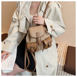 Dettaglio dello zaino vintage in tela con finiture in pelle e tasche con fibbia sul cappotto
