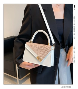 Detailed view of the crocodile textured flap and gold buckle on a stylish handbag