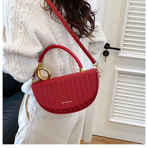 Détail du sac de selle rouge tressé avec boucle dorée et poignée ronde