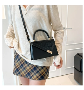 Detail of vintage black crossbody bag with faux crocodile texture and gold hardware