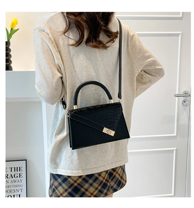 Detail of black crocodile pattern leather handbag with elegant gold metal twist lock