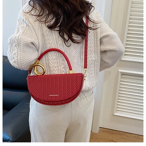 Gros plan d'un sac boîte rouge demi-lune avec texture tressée et détails dorés