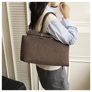Side view of dark brown suede tote bag featuring gold hardware on a model indoors
