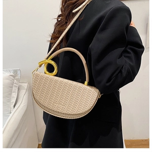 Détail du sac selle beige tressé avec boucle métallique en spirale et bandoulière chic