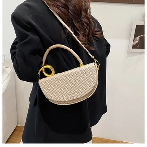 Détails d'un sac selle beige tissé avec poignée dorée et bandoulière sur le modèle