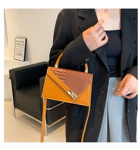 Detail of yellow and brown crocodile embossed handbag with gold buckle and top handle