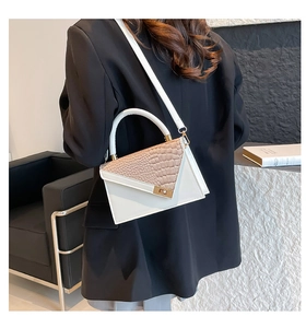 Detail of white crocodile pattern handbag with gold twist lock and adjustable strap