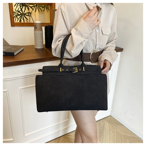 Close-up of black suede tote bag featuring elegant gold buckles and minimalist buckle straps