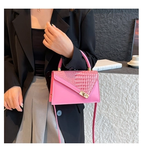 Close-up of pink croc-effect handbag featuring a metallic gold twist lock and top handle