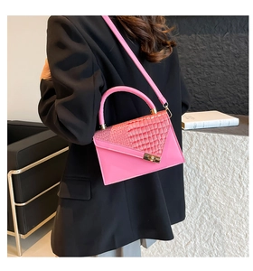 Close-up of pink faux crocodile leather texture and golden clasp on a stylish handbag