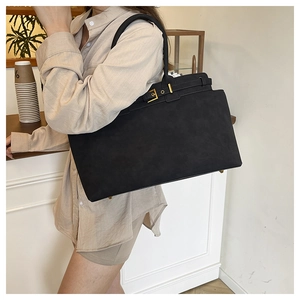 Macro view of black suede tote bag featuring premium golden metal buckle and leather strap