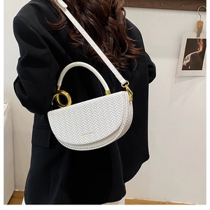 Détail du sac blanc à texture tissée avec ferrures dorées et boucle circulaire
