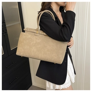 Detail view of beige suede tote bag with decorative gold buckle and metal hardware