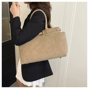Detail of khaki tote bag showing metallic bottom studs and decorative buckles