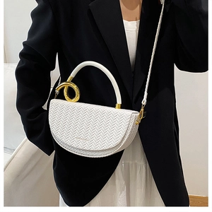 Détail d'un sac demi-lune tressé blanc avec anneaux dorés porté par un mannequin