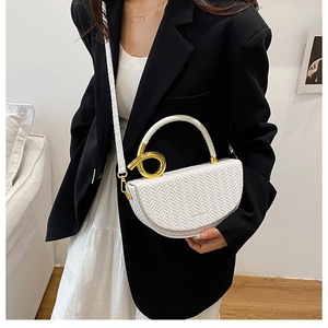 Détail d'un sac selle blanc tissé avec boucle dorée et bandoulière géométrique chic
