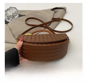 Vue détaillée d'un sac demi-lune tressé marron foncé avec finitions métalliques dorées