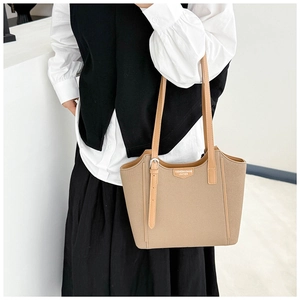 Khaki faux leather tote bag with elegant buckle and brand tag worn by female model
