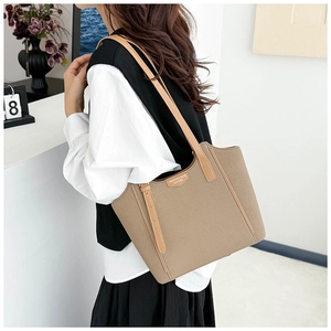 On-body view of large khaki canvas tote bag with brown handles and fashion patch