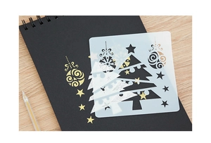 Vue détaillée du pochoir de Noël en PET translucide sur un carnet noir élégant