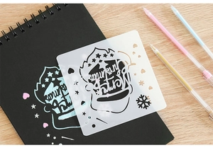 Détail du pochoir en plastique blanc avec motifs couronne et flocon sur un carnet noir élégant