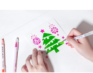 Détail d'une main coloriant un pochoir de Noël avec des feutres de couleur à double pointe