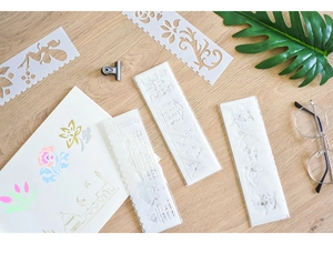 Close-up of white hollowed stencil set with floral and architectural patterns on wood