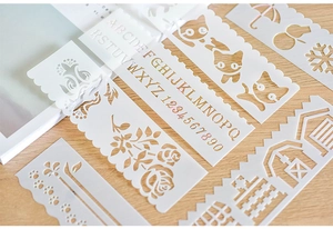 Close-up of white hollow stencil set with alphabet and floral patterns on wood surface
