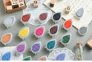 Flat lay of colorful teardrop-shaped luxury ink pads with vintage crafting accessories