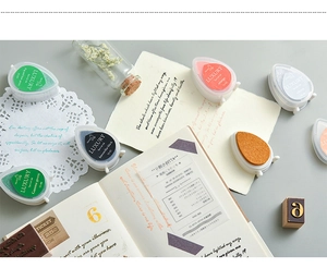 Macro shot of colorful teardrop ink pads with vintage stamps and journals for DIY crafts