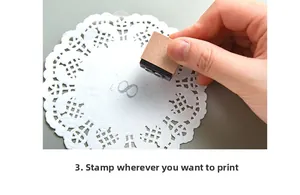 Detailed view of mini wooden stamp creating a grey infinity symbol on white lace paper