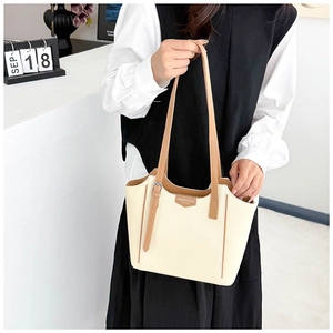 Detail of cream tote bag featuring brown leather strap and textured pebble finish