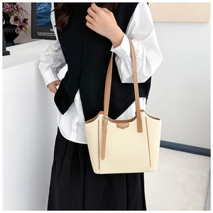 Detail of beige canvas tote with brown leather handles and brand label on front