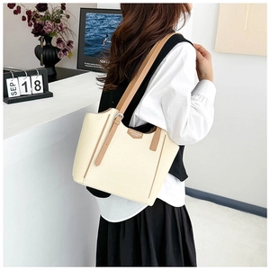 Detail of cream tote bag with brown leather side straps and metallic buckle accent